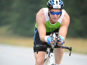 Dr. Sean Martin, owner of Transcend My Limits, seen riding a bike on a winding road.