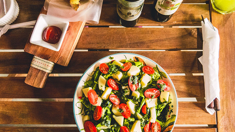 A picture of a healthy salad in a bowl on a dining table.