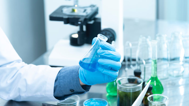 A photograph in a medical laboratory showing a specialist holding a tube.