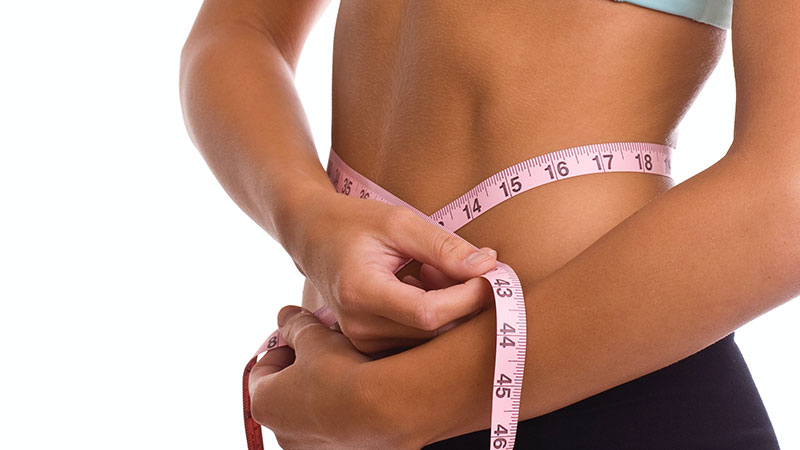 A photograph showing a woman who has a tape measure around her waist.