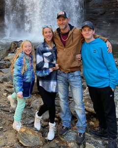 A photograph of a happy family standing in front of a waterfall.